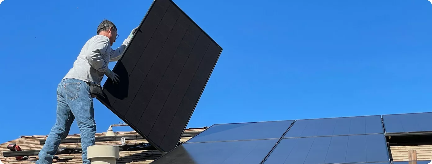 Operario instalando placas solares en vivienda