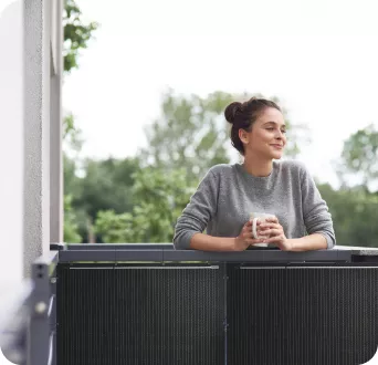 Mujer asomada en balcón con Kits de placas solares instalados