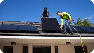 Trabajadores instalando placas solares en el tejado de una vivienda